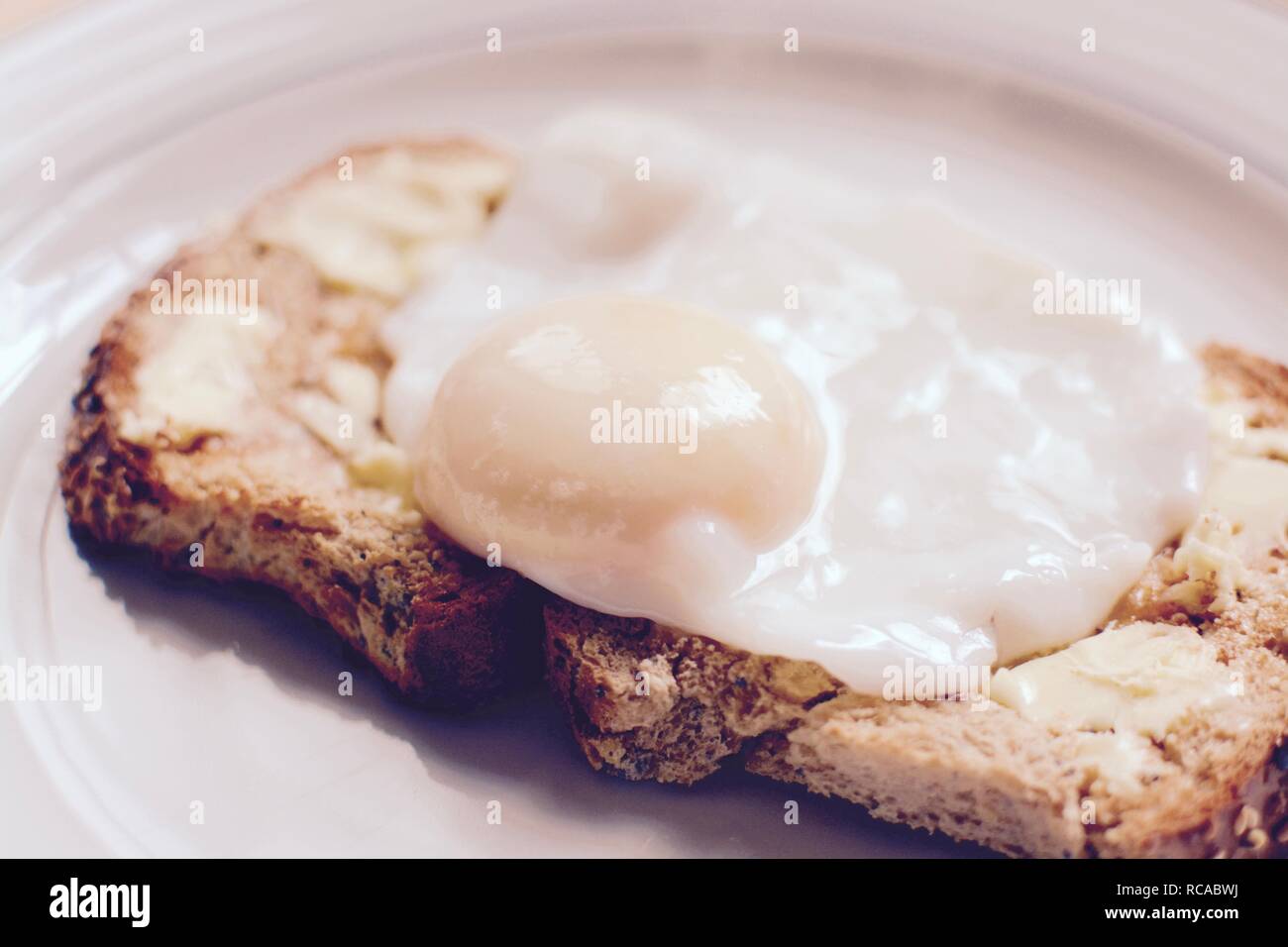 The perfect poached egg on seeded buttered brown toast - filter applied Stock Photo