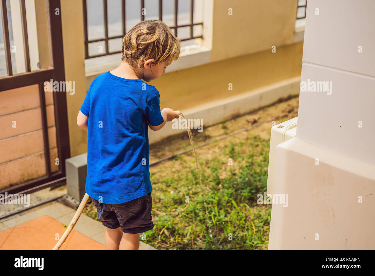 Cute little toddler boy watering plants with watering can in the garden