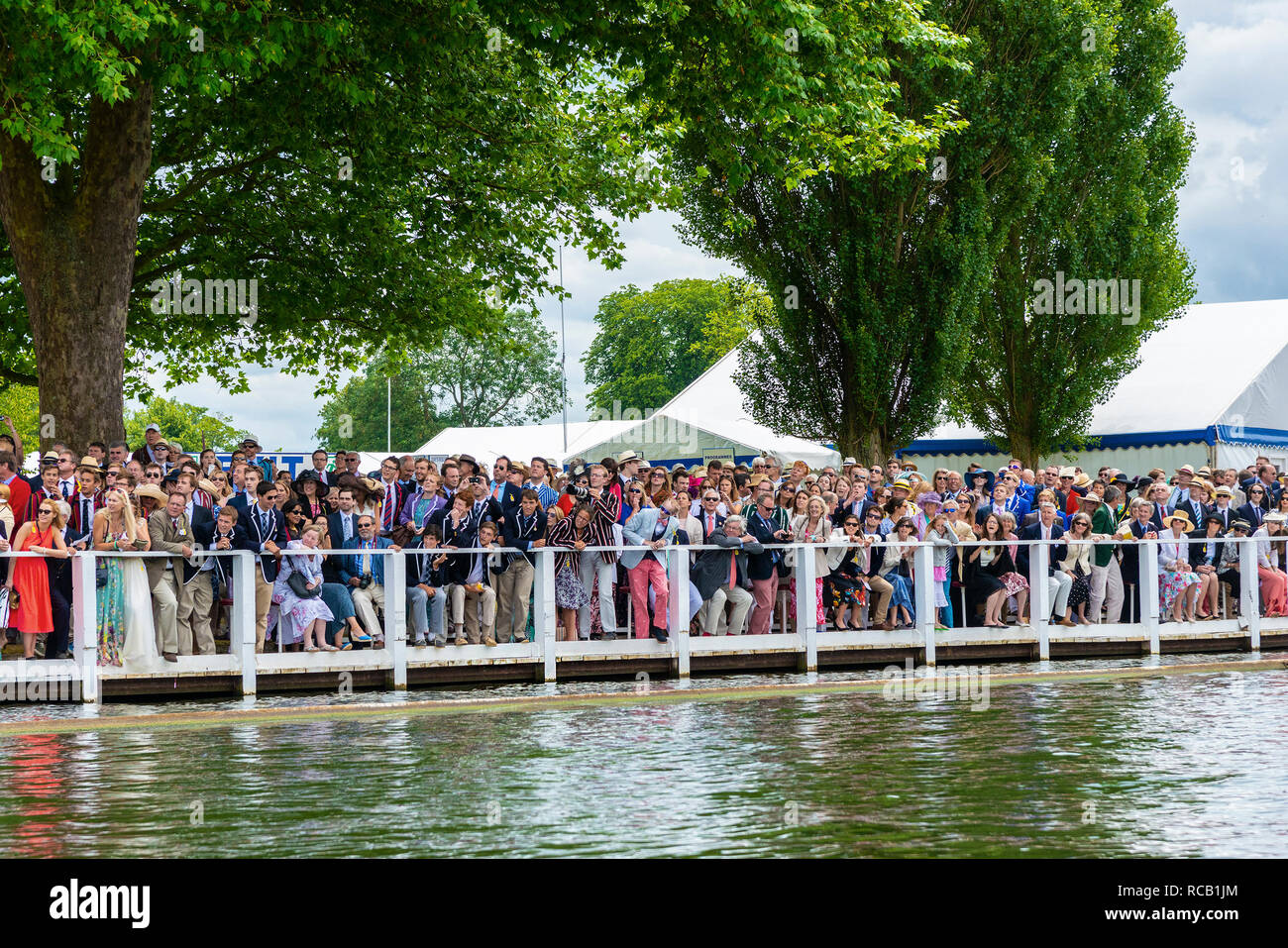 Spectators in the Stewards Enclosure wait for the next rowing race to come past at the Henley Royal Regatta, Henley-on-Thames, England, UK Stock Photo