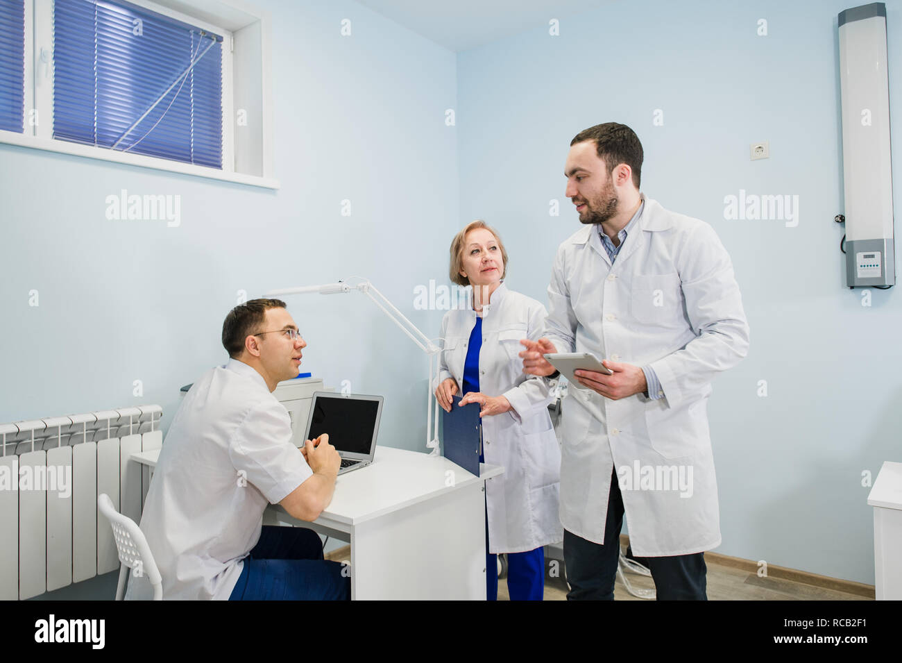 Medical staff discussing over medical reports using laptop and tablet pc. Healthcare professionals having discussion in hospital office. Stock Photo