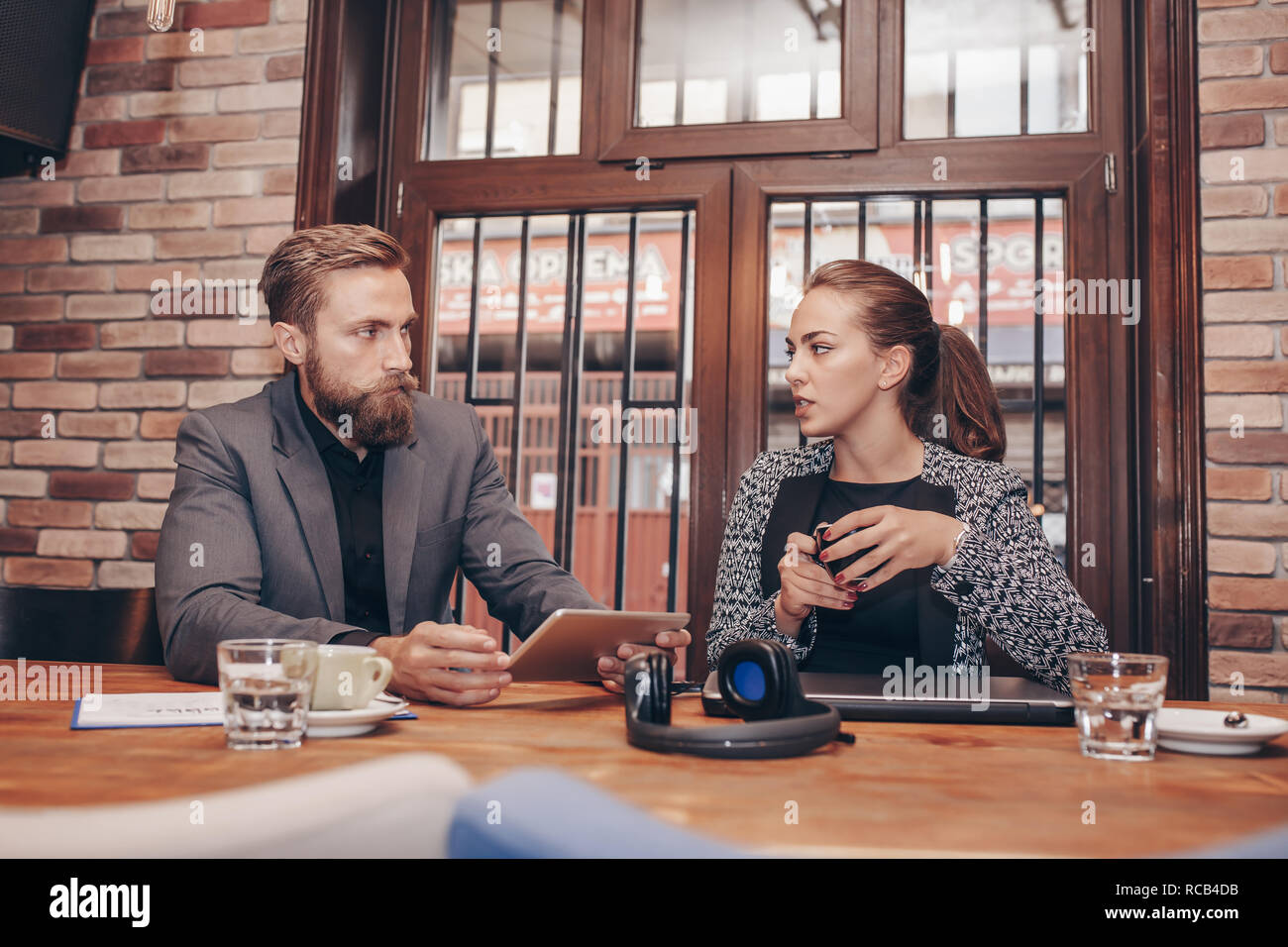 Businesspeople discussing while using digital tablet and drinking coffee while working in cafe Stock Photo