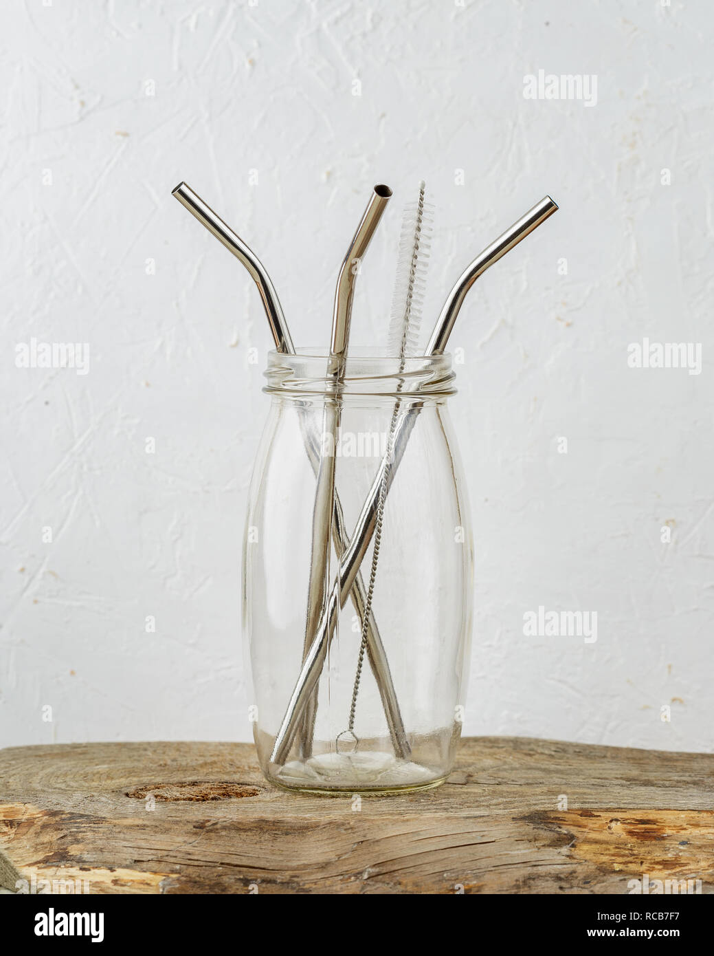 Three reusable metal drinking straws and cleaning brush in a jar over grey background. Zero Waste and minimalism lifestyle Stock Photo