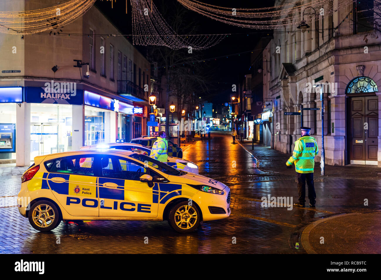 Ramsgate bomb suspected bomb incident on 14 January 2019. Police cars with blue flashing lights help cordon off the town centre, night time. Three police cars and some policemen parked on cross roads on town, city street. Stock Photo