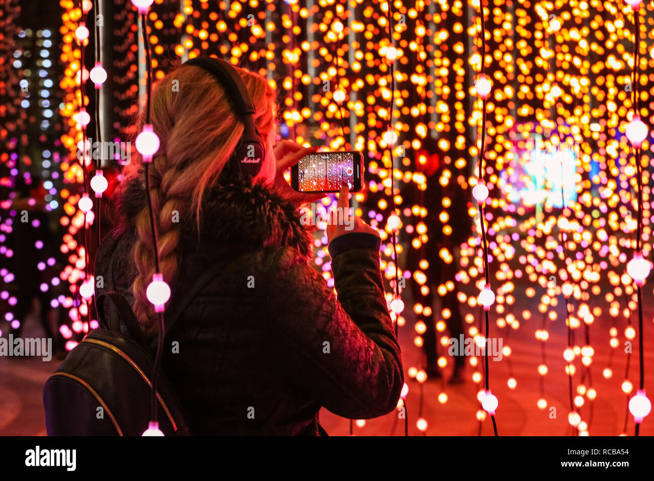 Canary Wharf, London, UK, 14th Jan 2019. People interact with and take  selfies with the 'Submergence' installation, a large work incorporating  strings of hanging lights by arts collective Squidsoup. The colourful Canary