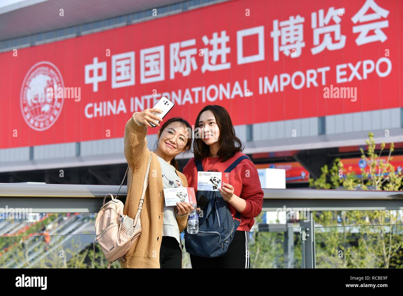 (190115) -- BEIJING, Jan. 15, 2019 (Xinhua) -- Visitors Chen Fei (L) and Weng Jingyi pose for photos in front of the venue of the first China International Import Expo (CIIE) in Shanghai, east China, Nov. 9, 2018. China's foreign trade rose 9.7 percent year on year to a historic high of 30.51 trillion yuan (about 4.5 trillion U.S. dollars) in 2018, the General Administration of Customs (GAC) said Monday. Exports rose 7.1 percent year on year to 16.42 trillion yuan last year, while imports grew 12.9 percent to 14.09 trillion yuan, resulting in a trade surplus of 2.33 trillion yuan, whic Stock Photo