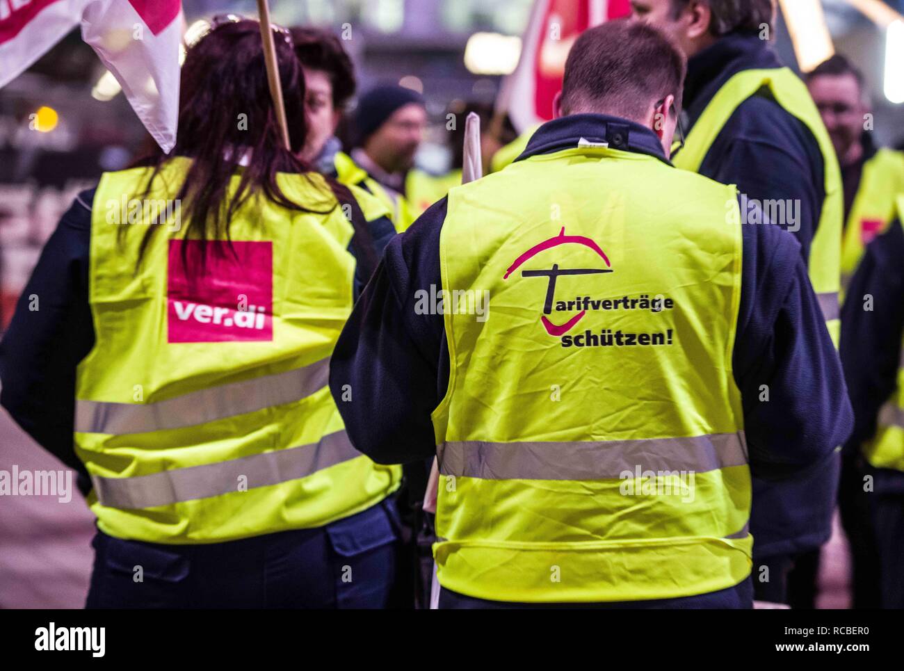 Munich, Bavaria, Germany. 15th Jan, 2019. The logo of the Verdi union and ''protect work contracts'' worn by striking airport security workers in Munich, Germany. Citing a breakdown in talks with employers on December 21st, the German Ver.di union organized the latest warning strike in a series at the Munich International Airport with members employed in Airport Security Services (Luftsicherheit) walking out from 3:30am to 24:00. The union is demanding 20 Euros per hour for their 1,000 total members working in Passenger-, Freight, Personnel, and Goods Control of Airport Security, along wi Stock Photo