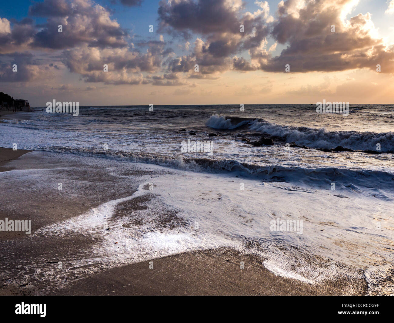 Sunset beach with rough seas and crashing waves. Stock Photo