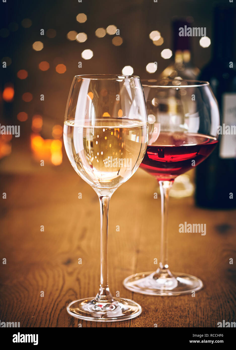 Glasses of red and white wine on a wooden table with sparkling party lights bokeh background Stock Photo