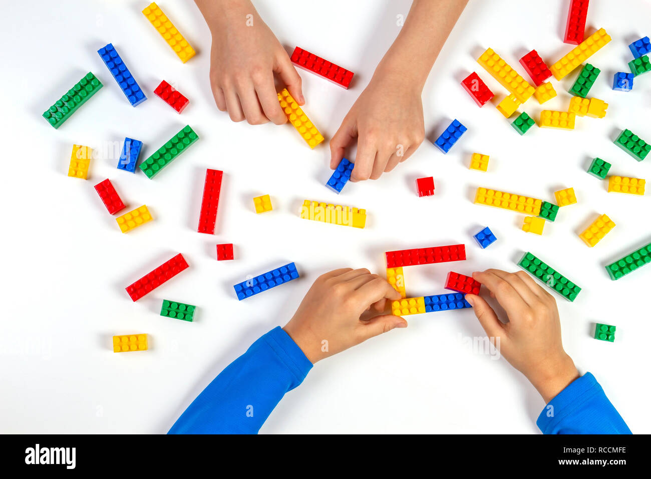 Kids hands playing with colorful building plastic bricks on white ...