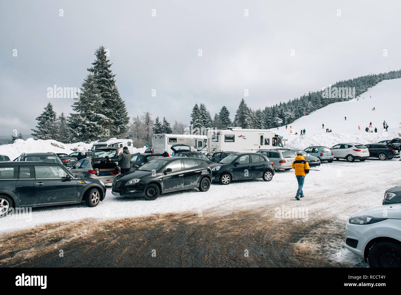MUMMELSEE, GERMANY - FEB 18, 2018: Snow and ski slope seen from parking area with people kids, parents having fun in German mountains Stock Photo