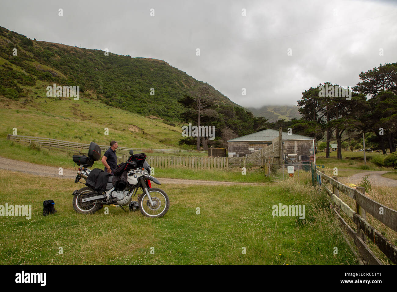 Flea Bay, Canterbury, New Zealand - January 6 2019: a man on a motorbike takes a break at the end of the windy road down into the bay Stock Photo