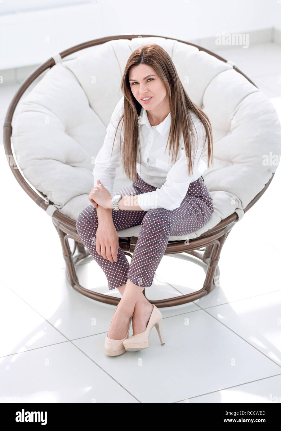 Confident Young Woman Sitting In A Soft Round Chair Stock