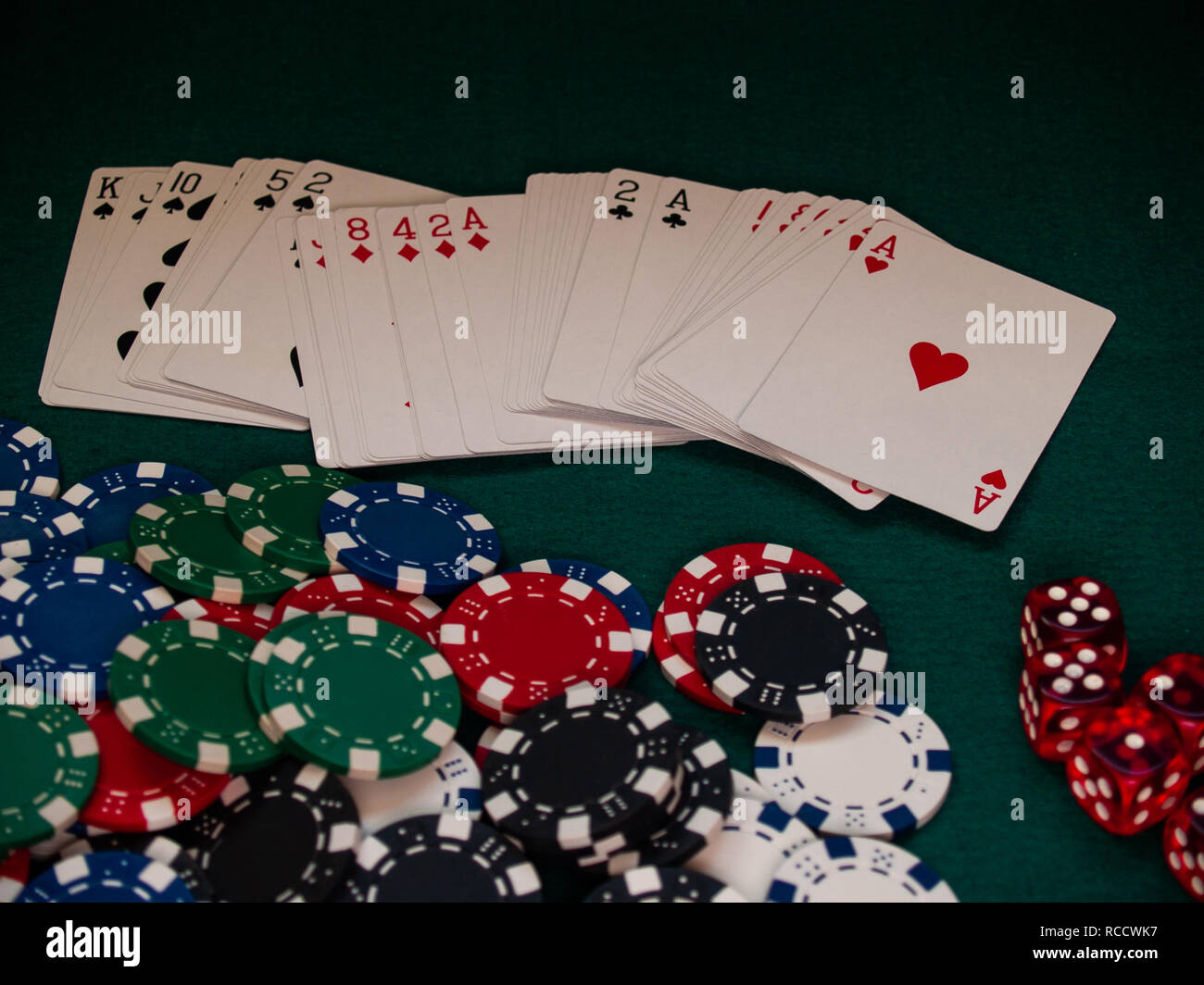 A poker deck, poker chips of different colors and several dice on a
