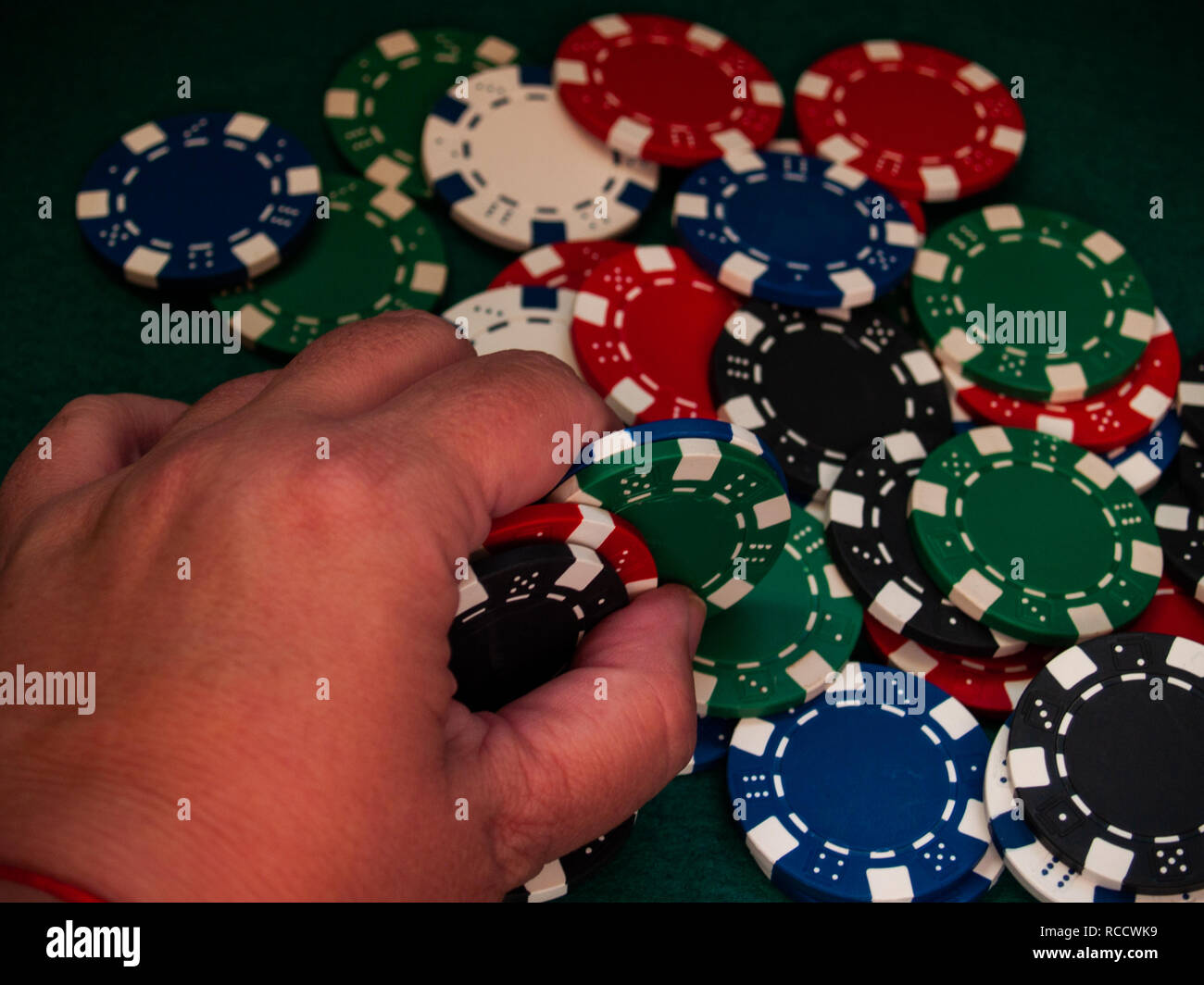 A person holding poker chips of various colors with his hand Stock Photo