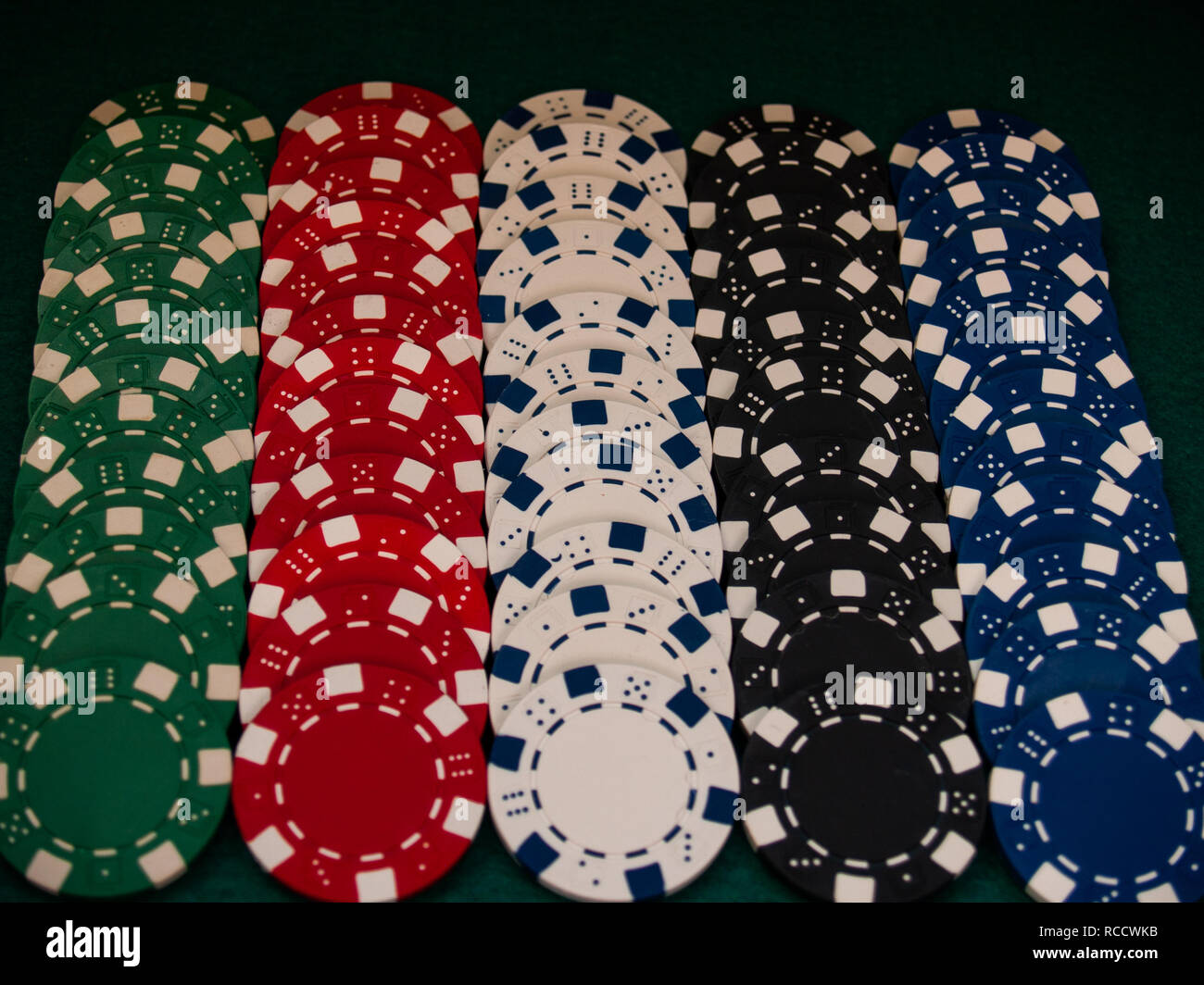 Poker chips of various colors on a green mat Stock Photo