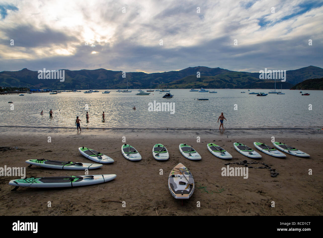 Akaroa, Canterbury, New Zealand - January 5 2019: paddleboards on the beach at Akaroa ready to be hired by tourists on a hot summer evening Stock Photo