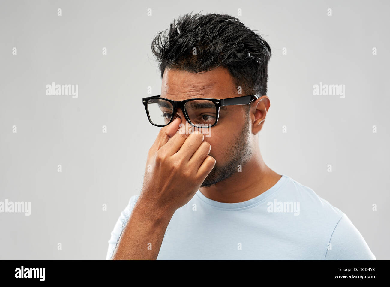 tired indian man in glasses rubbing nose bridge Stock Photo