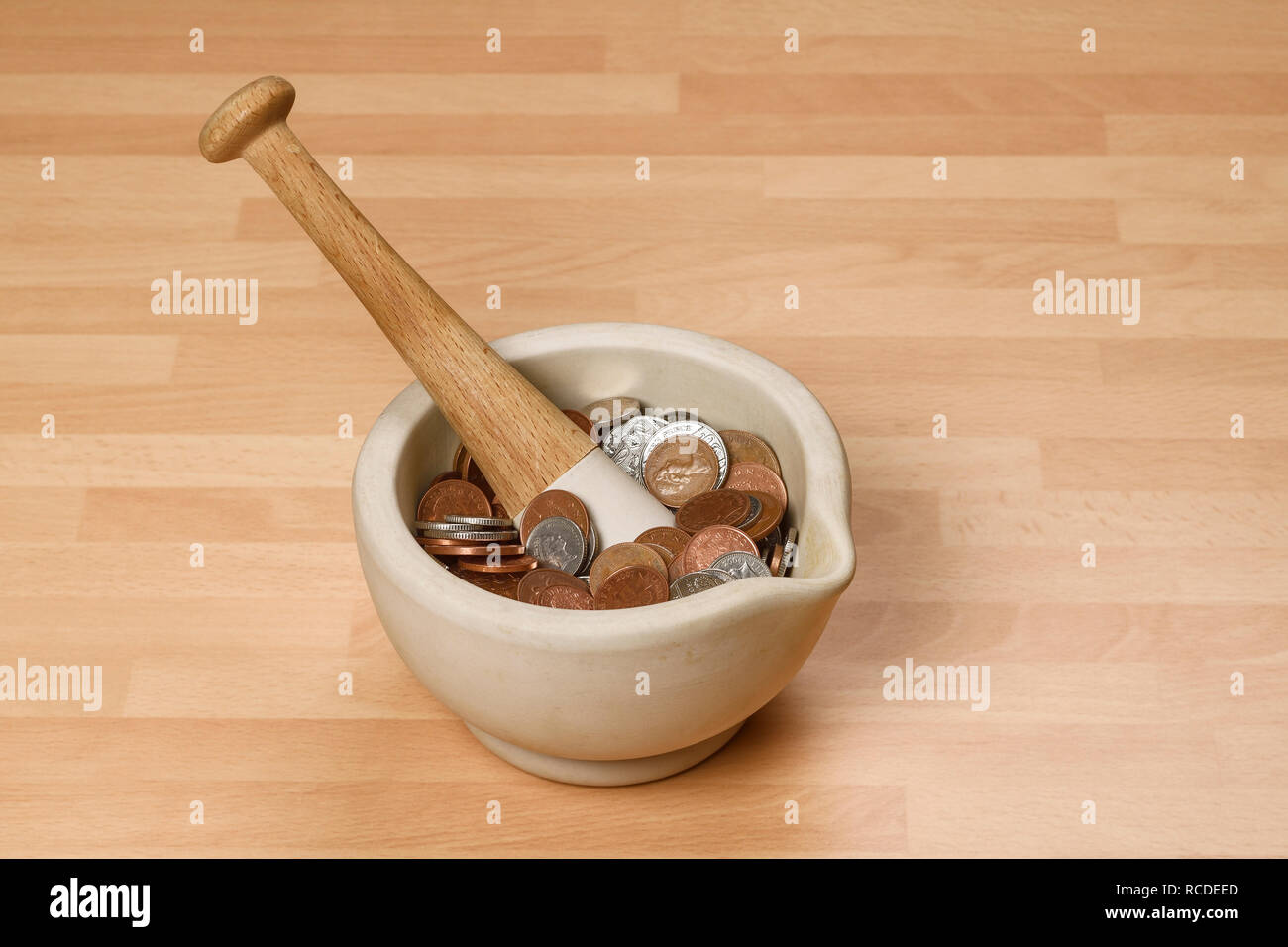 A pestle and mortar filled with UK pound sterling coins Stock Photo