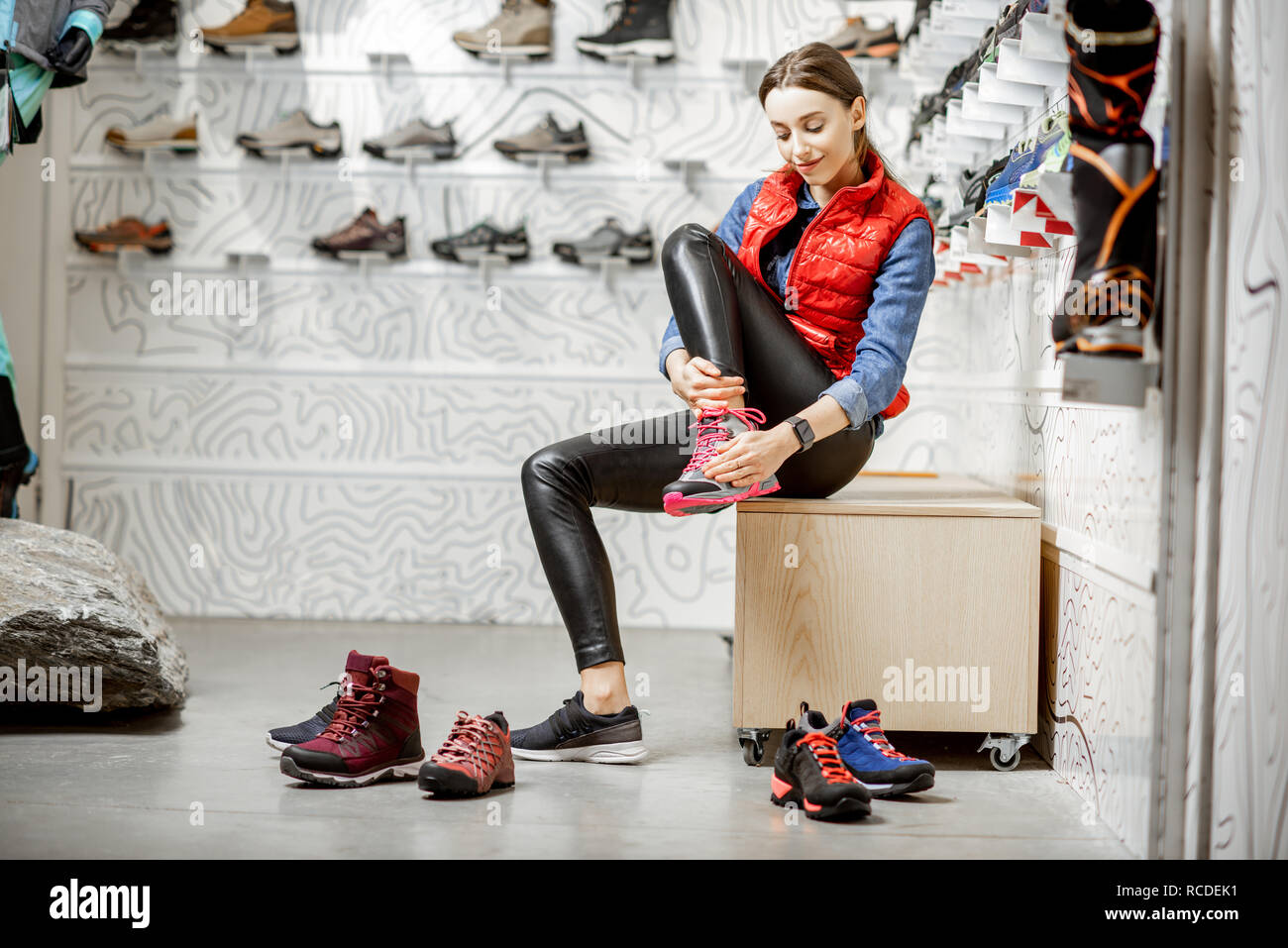 Woman trying shoes for mountain hiking sitting in the room of the modern sports shop Stock Photo - Alamy