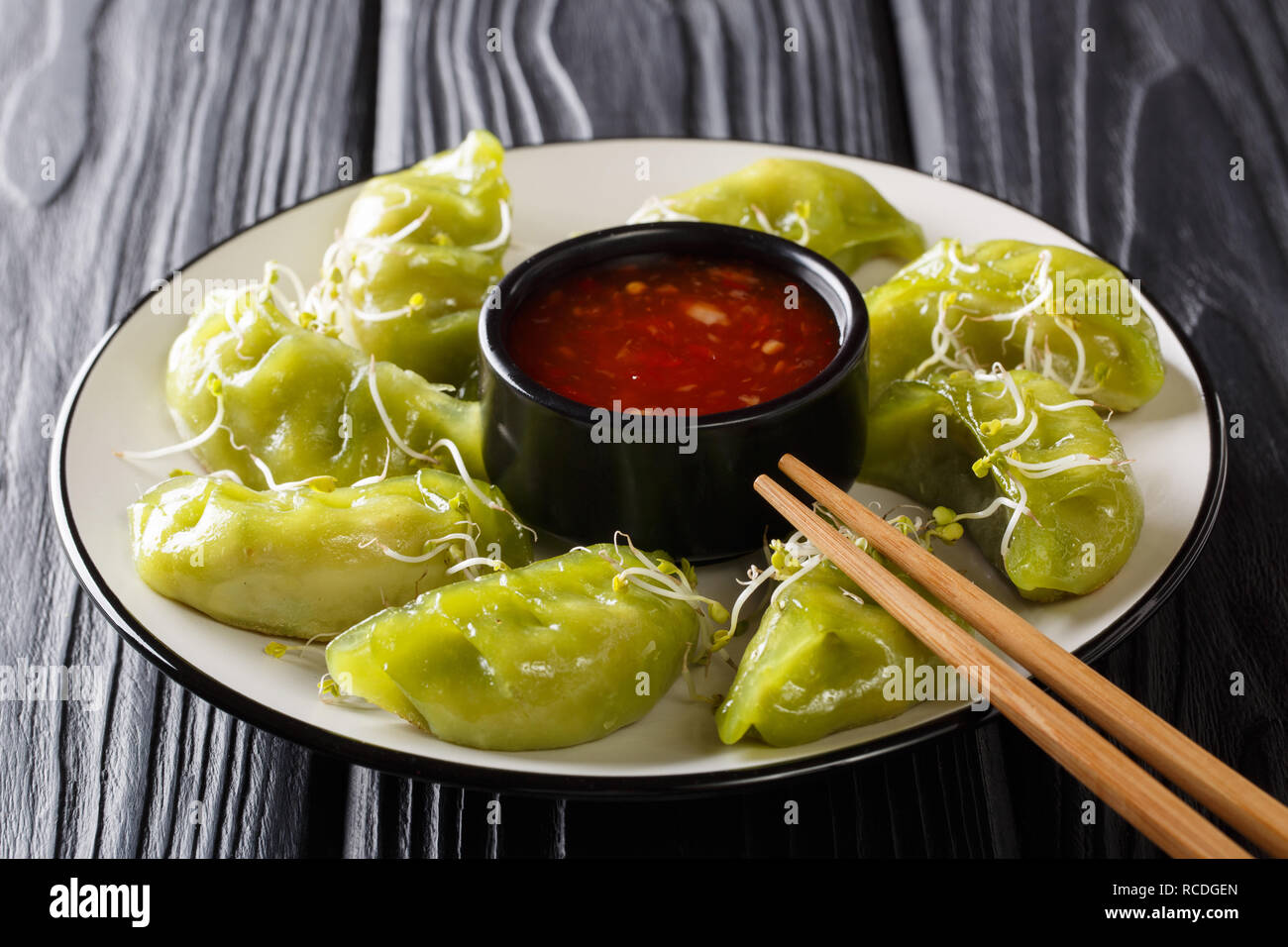 Japanese traditional cuisine gyoza with matcha served with spicy sauce and microgreen close-up on a plate on the table. horizontal Stock Photo