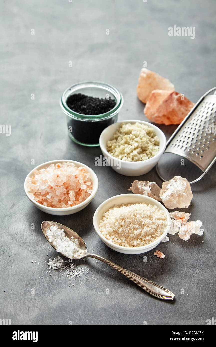 Containers of assorted natural culinary salts with rock and sea salt
