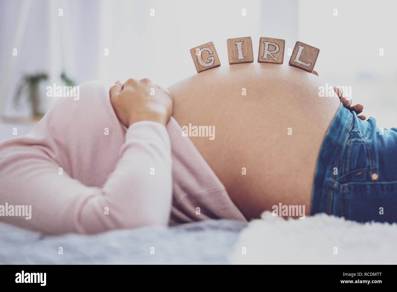 Pregnant woman holding bricks saying Girl on belly Stock Photo