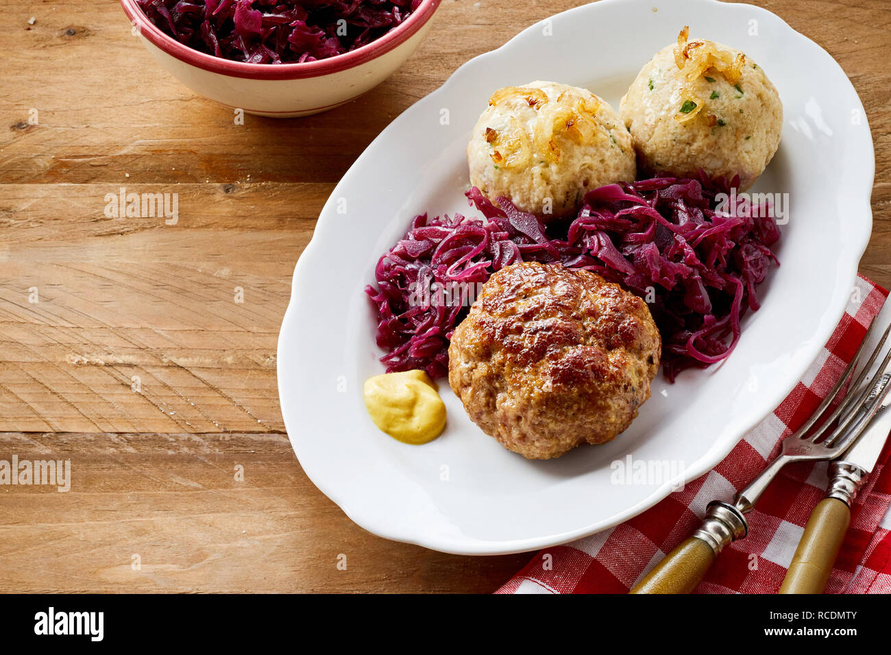 German meatball and dumplings served with red cabbage sauerkraut and a dollop of mustard on an