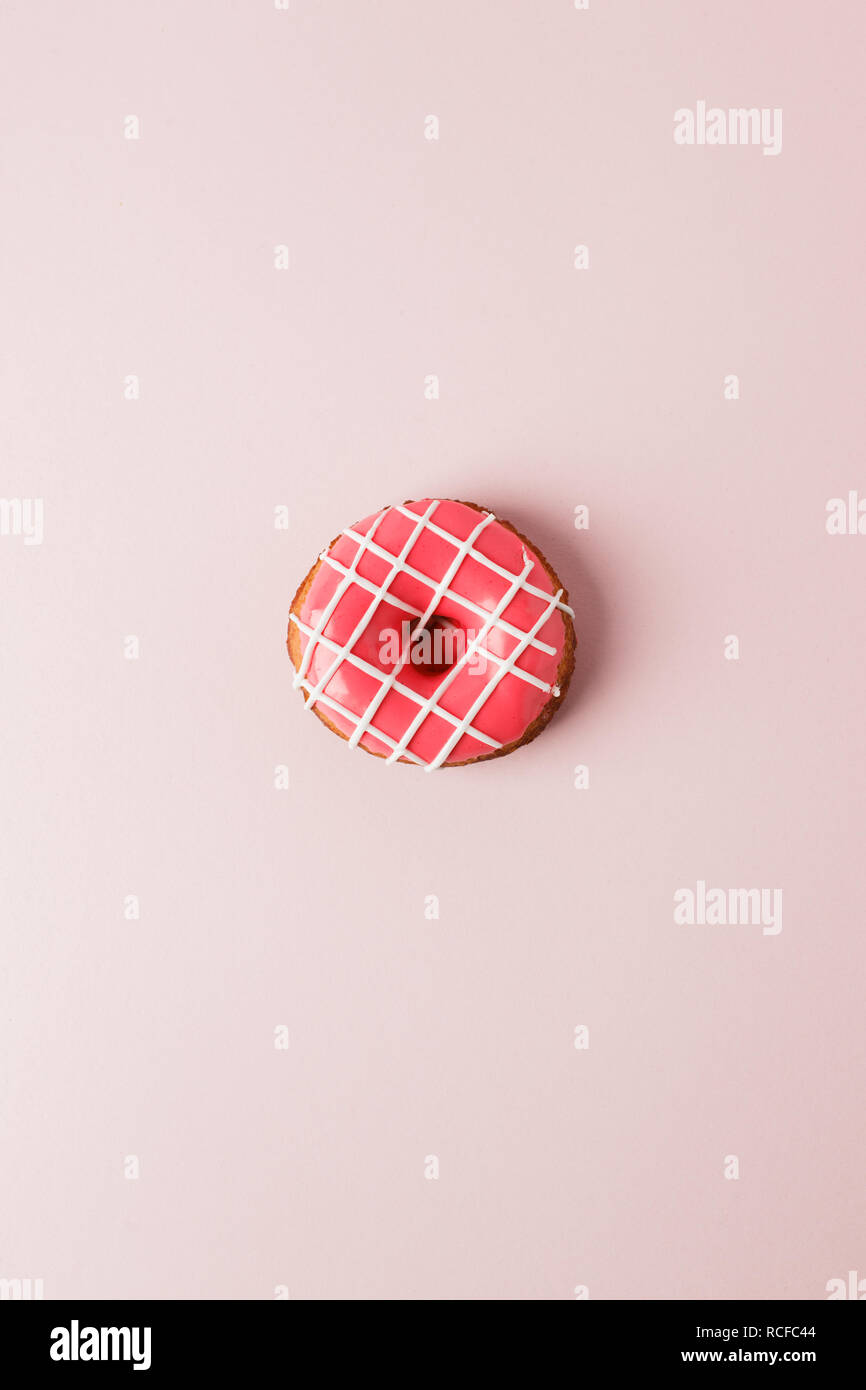 One pink live coral donut on pink background, monochrome seet unhealthy food concept, flat lay, top view, copy space Stock Photo