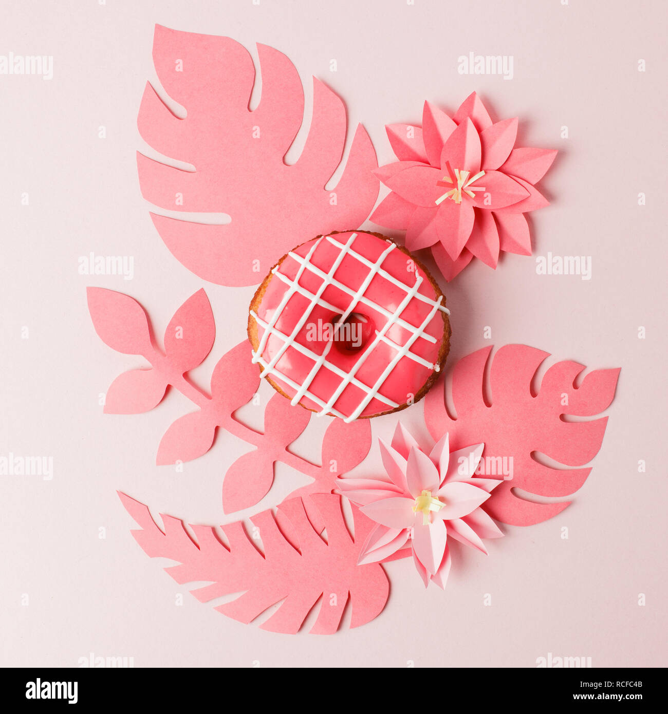 Handcraft plant corner from live coral paper with tropical leaf and donut.  A modern handmade paper application from colored paper on pink background. Stock Photo