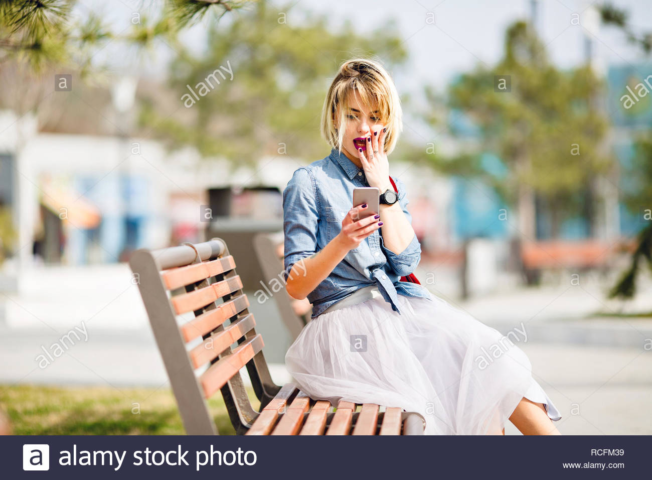 Young Cute Blond Girl With Short Hair Sitting On A Wooden