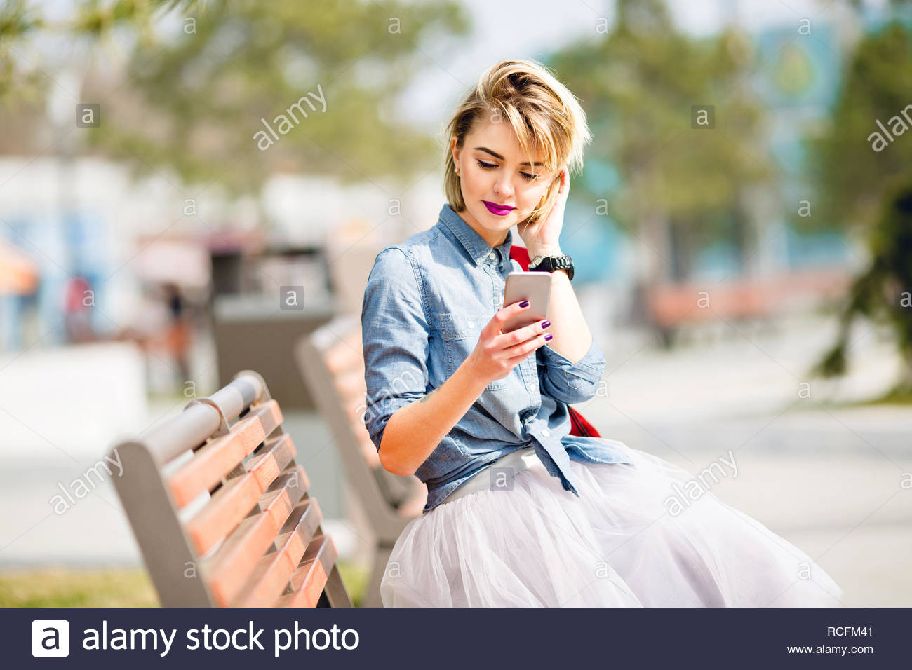 Young Cute Blond Girl With Short Hair Sitting On A Wooden