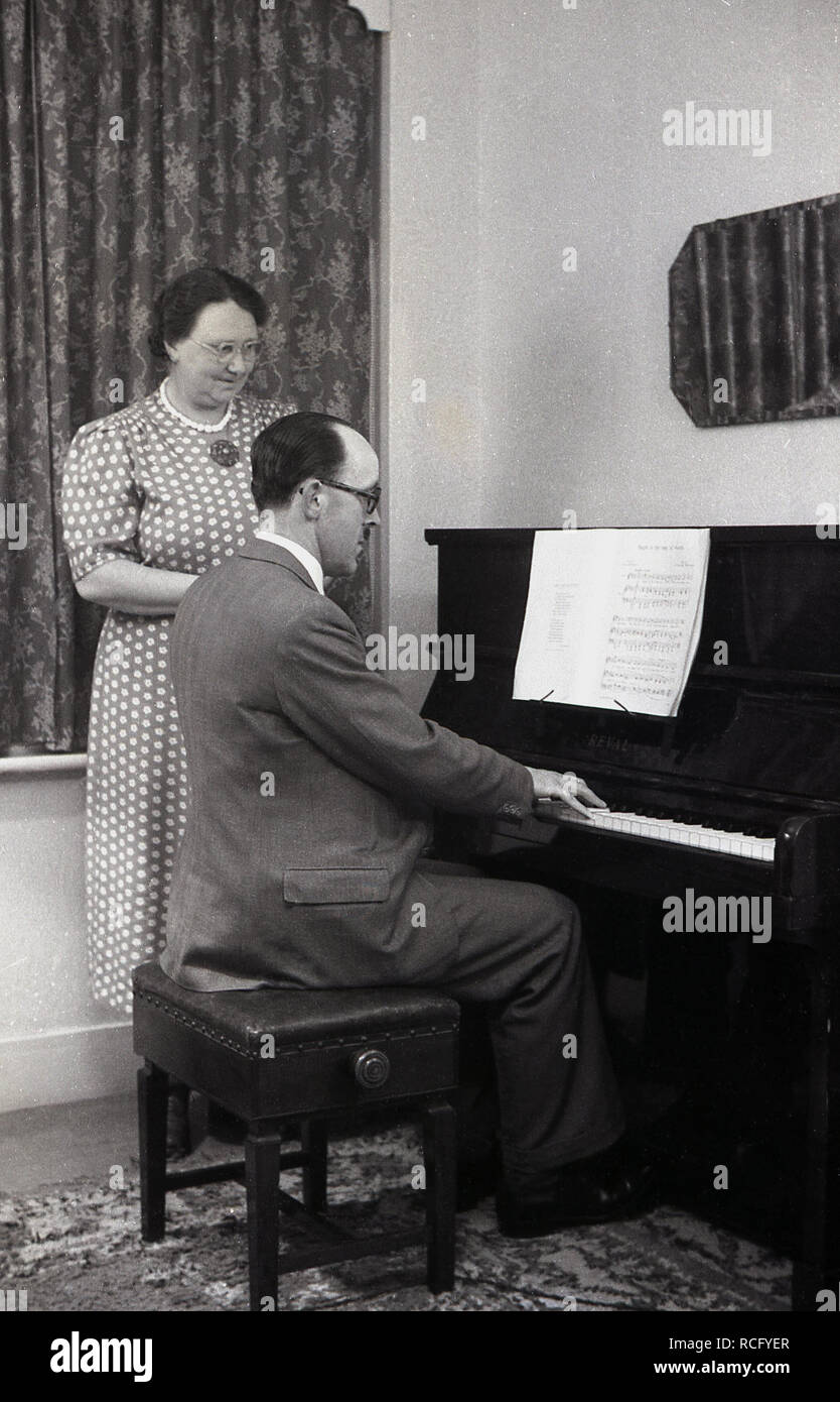 Woman playing piano man watching hi-res stock photography