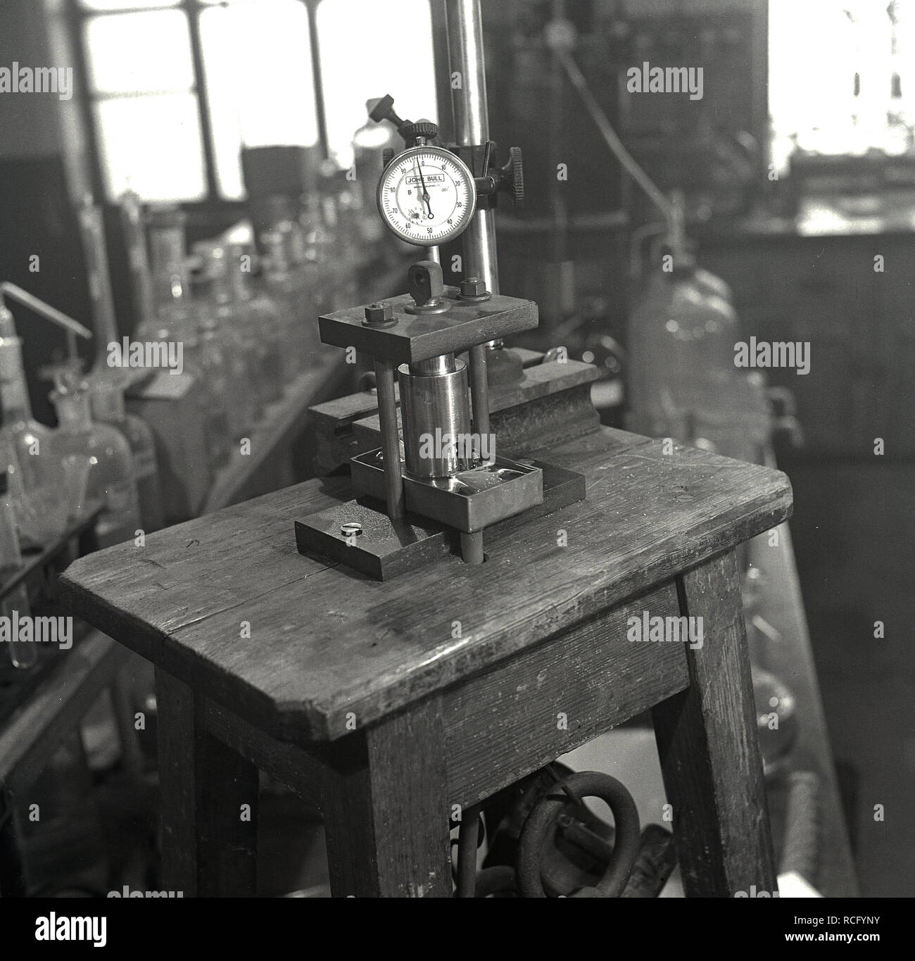 1950s, historical, a science laboratory, on a small wooden work bench, a 'John Bull' instrument, a dial test gauge fixed on table, Leeds University, Leeds, England, UK. The 'John Bull' testing equipment of the era was made British Indicators Ltd of Pickford Rd, St Albans, England, UK, a leading manufacturer of precision internal gauging and measuring equipment. Stock Photo