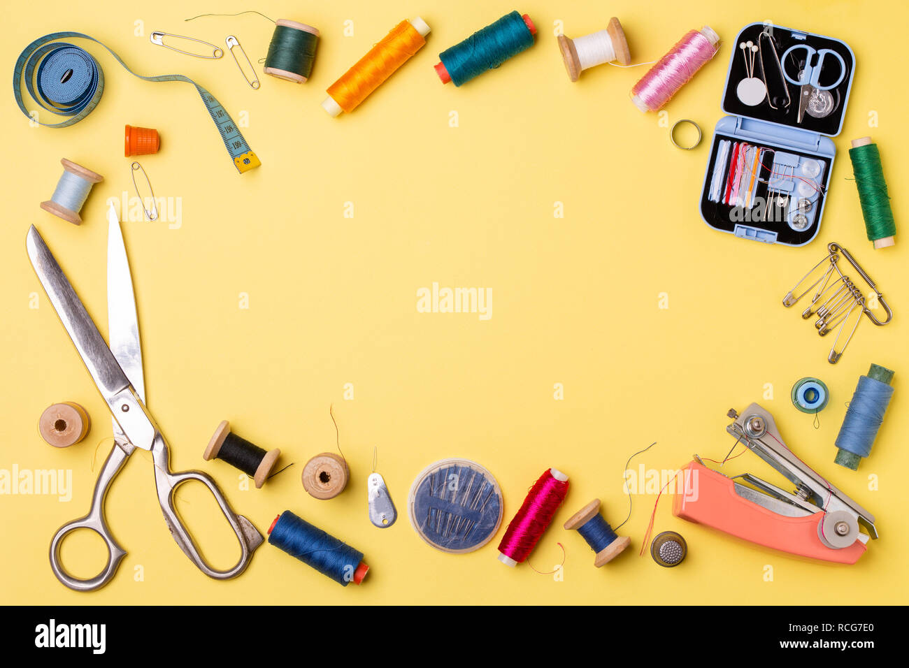 Composition with threads and sewing accessories - scissors, centimeter, pins on yellow background. Stock Photo