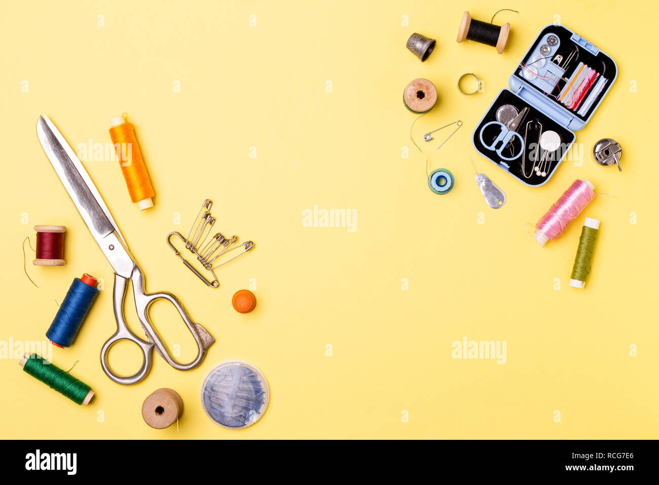 Composition with threads and sewing accessories - scissors, centimeter, pins on yellow background. Stock Photo
