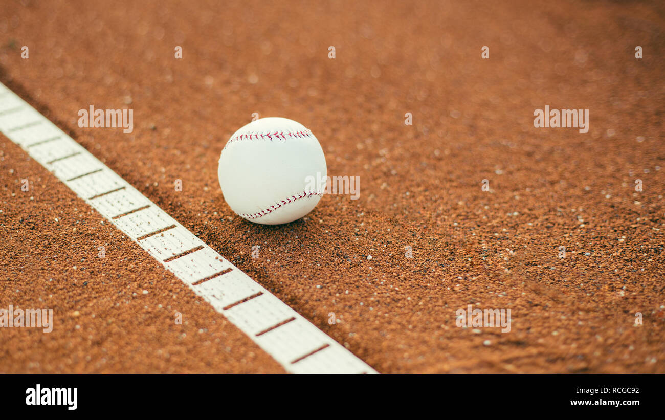 Baseball ball on pitchers mound. Baseball field at sunset Stock Photo
