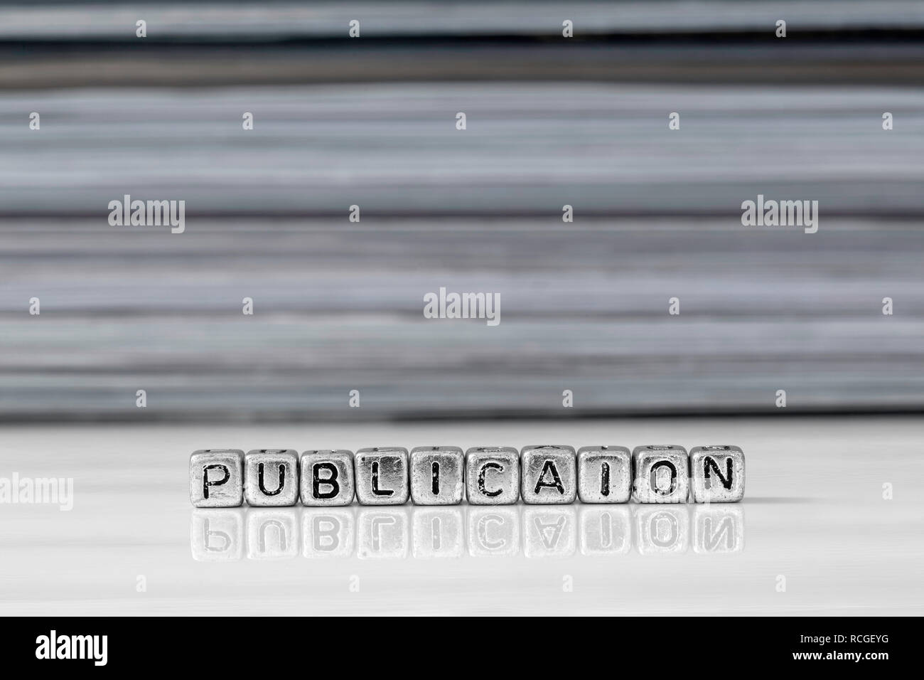 Publication on beads with magazines stacked in the background reflected on a white surface Stock Photo