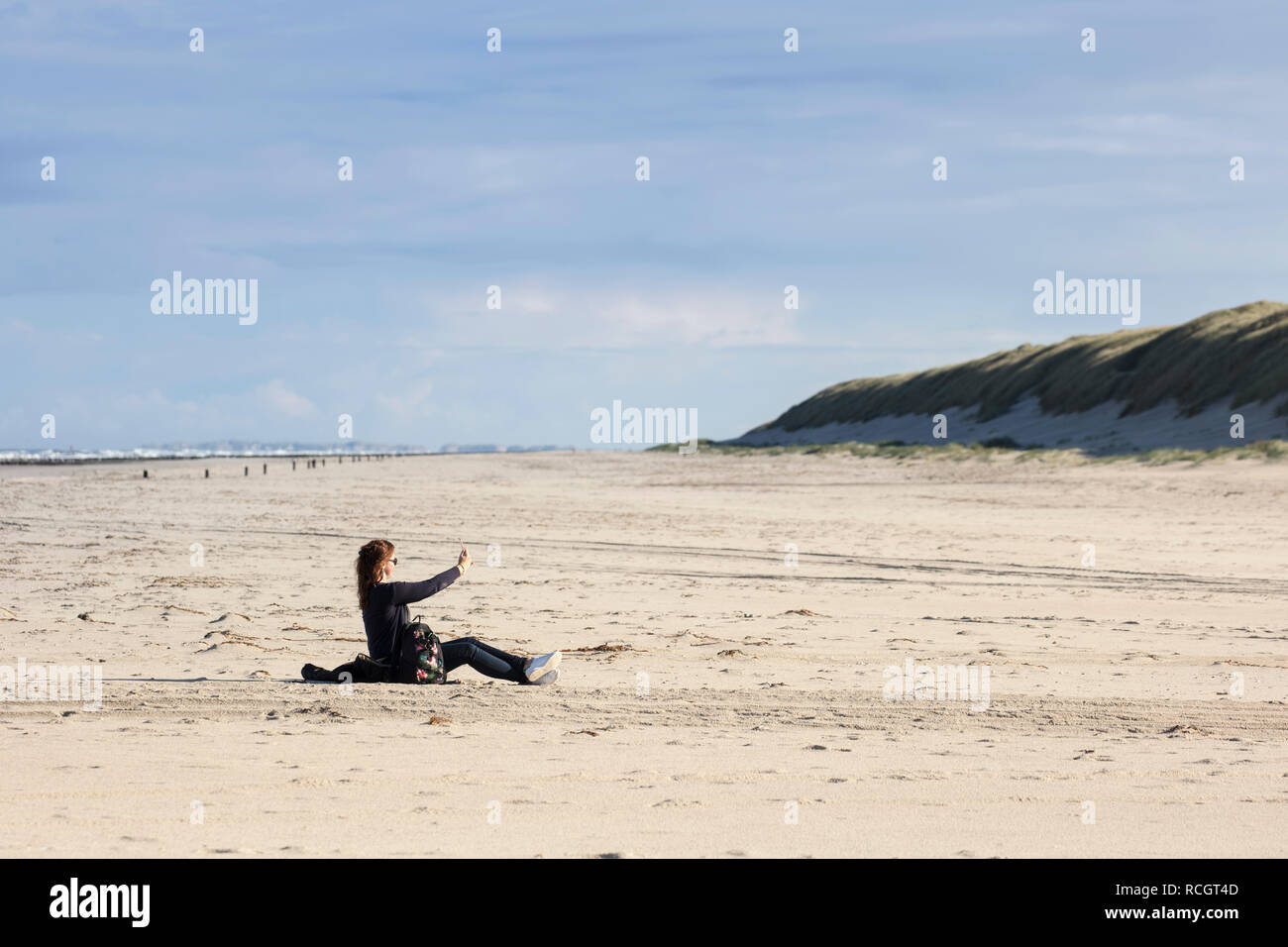 The Netherlands, Vlieland, North Sea beach. Woman takes selfie. Stock Photo