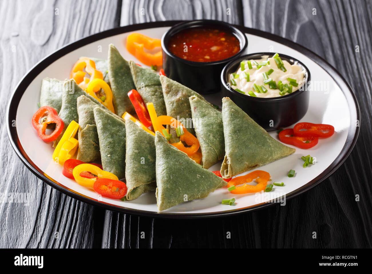 Asian spinach samosa with pepper and two sauces close-up on a plate on the table. horizontal Stock Photo