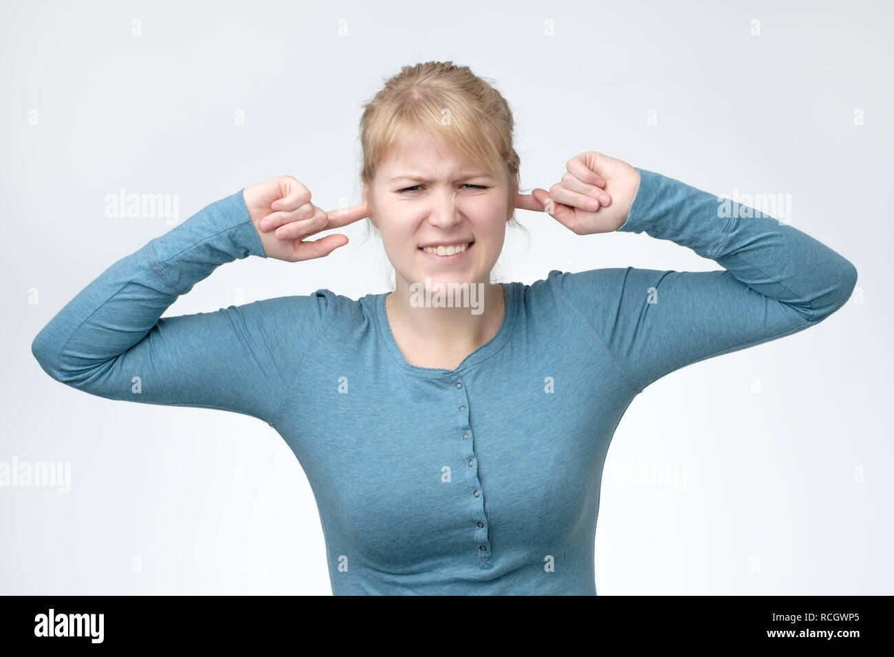 Beautiful european woman with plugging ears, closing her eyes, pretending not to hear what she is told. Unpleasant music or noise Stock Photo