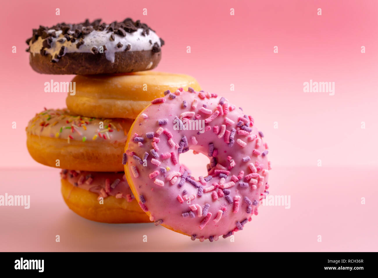 Stack of colorful donuts on pink background. Stock Photo