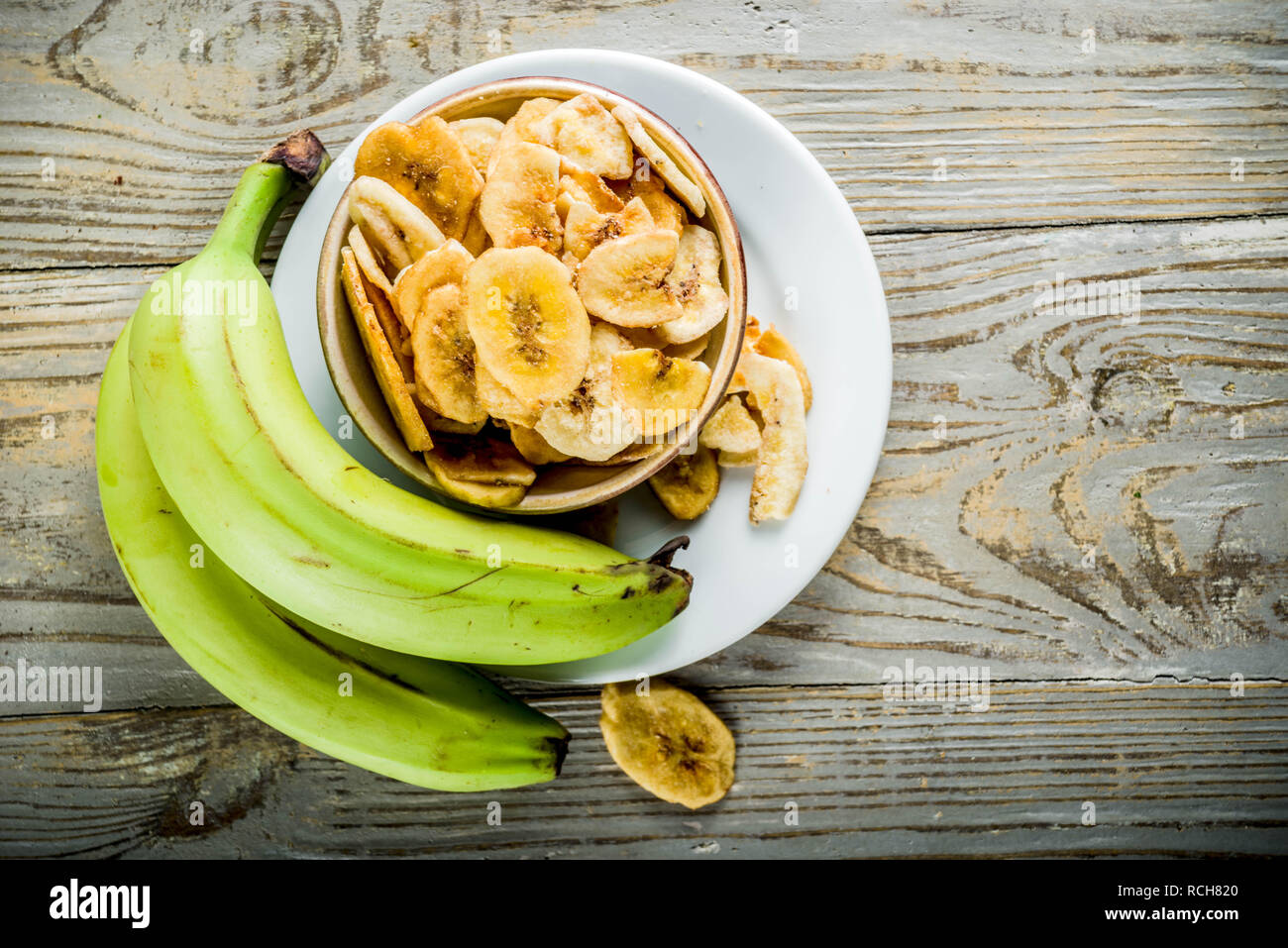 Dried bananas plantains with fresh bananas, wooden background copy