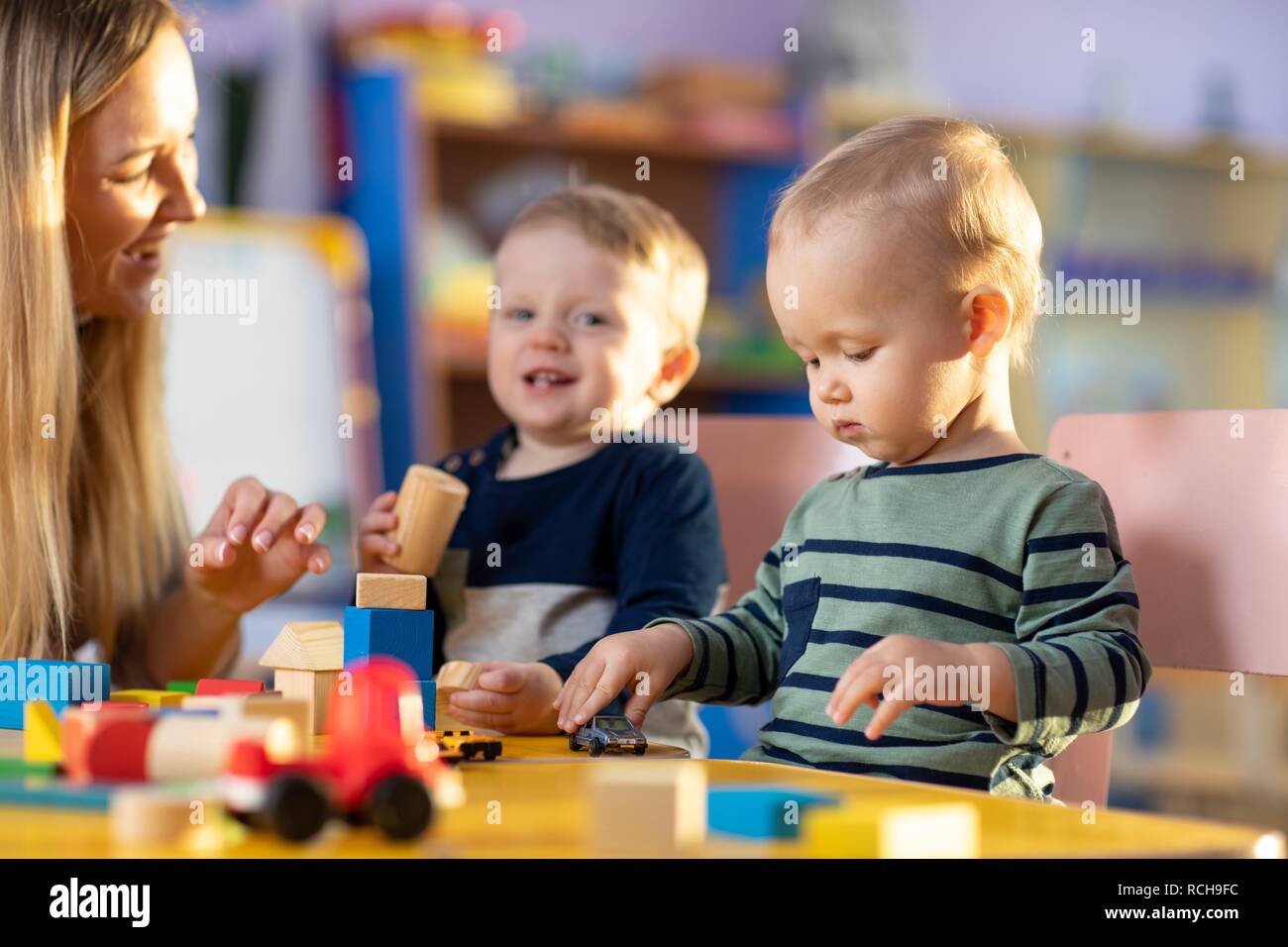 Preschool teacher and cute children boys having fun time playing Stock Photo