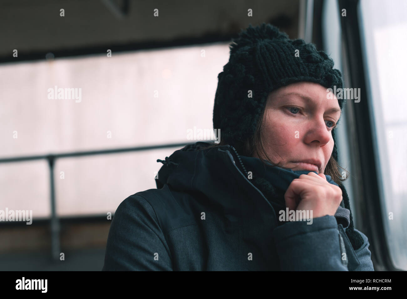 Sad woman on the bus looking through window at the street on cold winter day Stock Photo