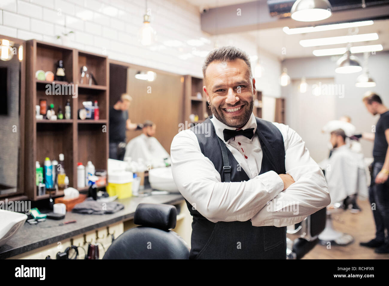 Young haidresser and hairstylist standing in barber shop. Stock Photo