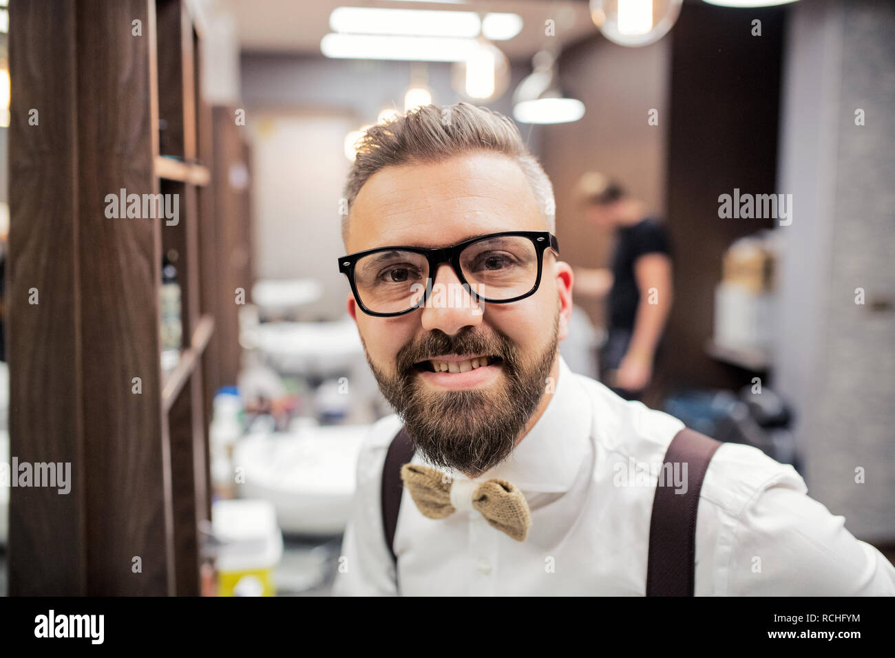 A portrait of handsome hipster man client standing in barber shop. Stock Photo