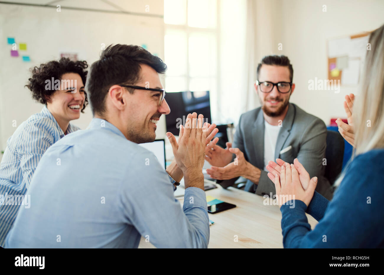 Group of young businesspeople sitting around table in a modern office ...