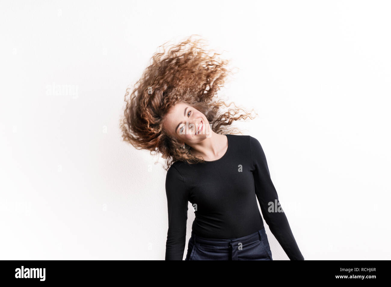 Young beautiful happy woman in studio, wind in the hair. Stock Photo