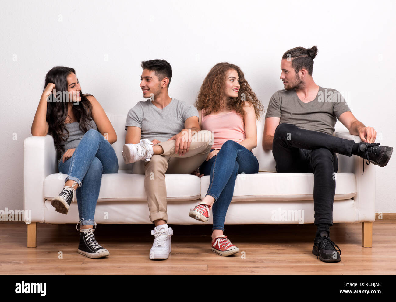 Portrait of young group of friends sitting on a sofa in a studio ...