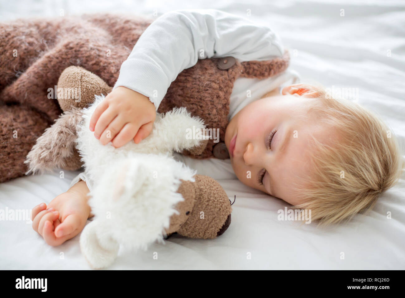 Sweet baby boy in cute overall, sleeping in bed with teddy bear ...